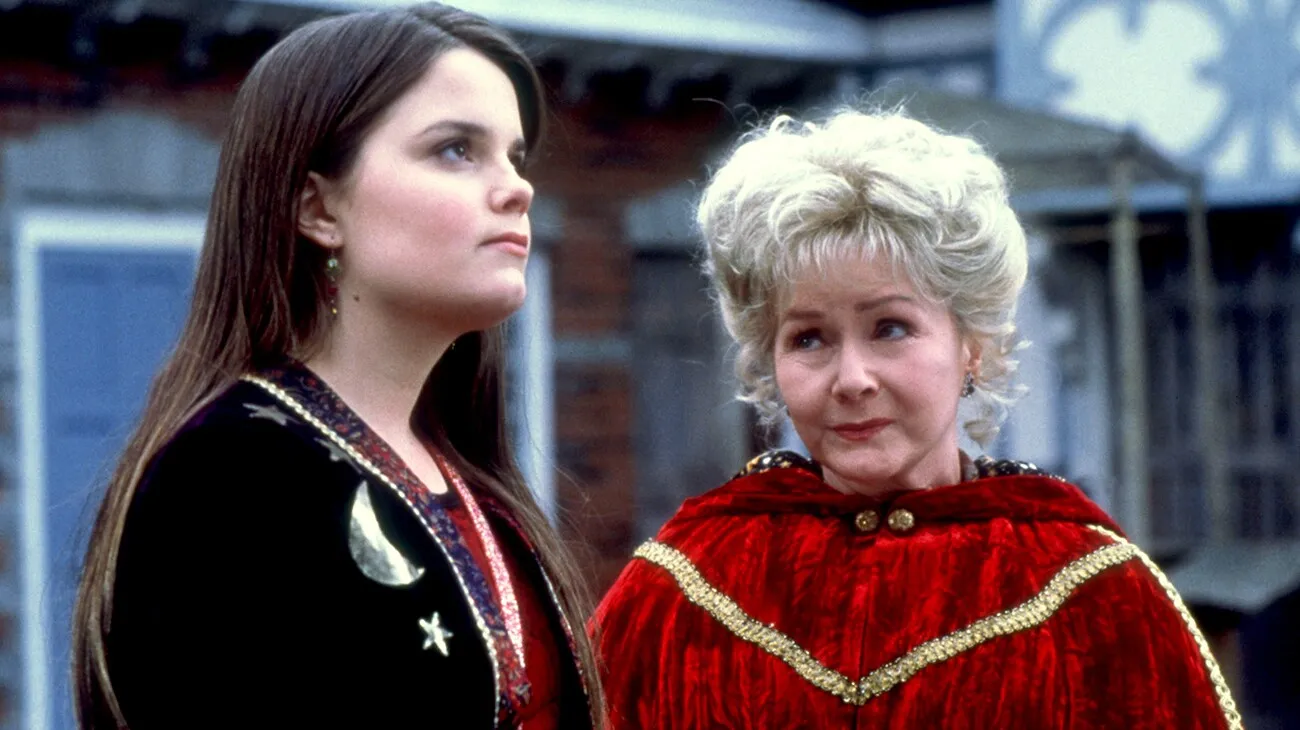 Marnie stands beside Aggie, who wears a red velvet cloak trimmed in gold.