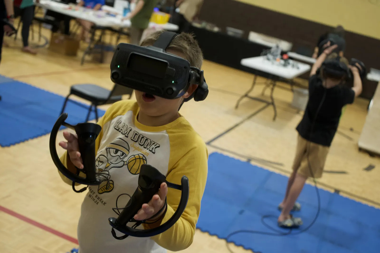 A young player using a VR headset and controllers during a supervised gaming activity