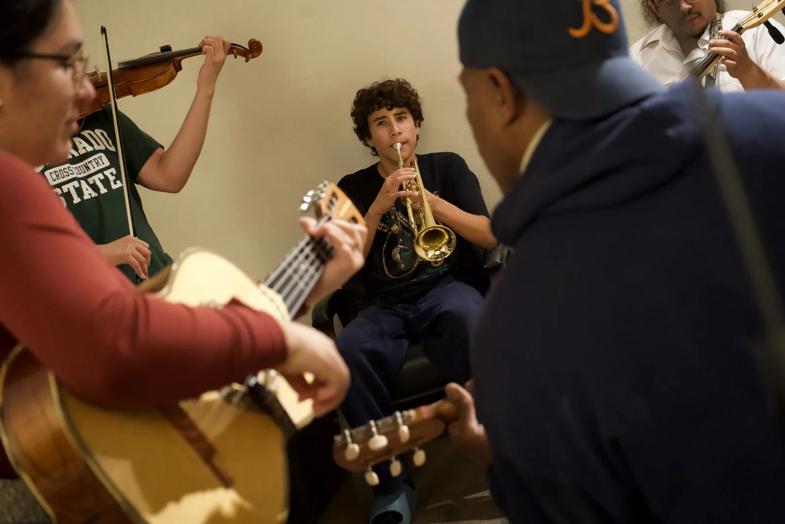 Musicians rehearse together with violin, trumpet, and guitarrón.