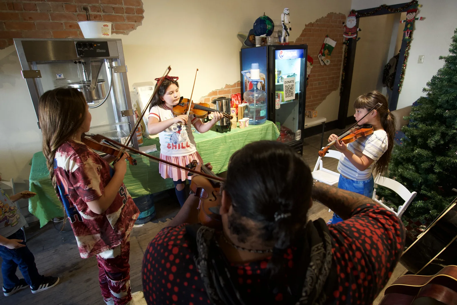 Young violinists practice together in a small rehearsal room.