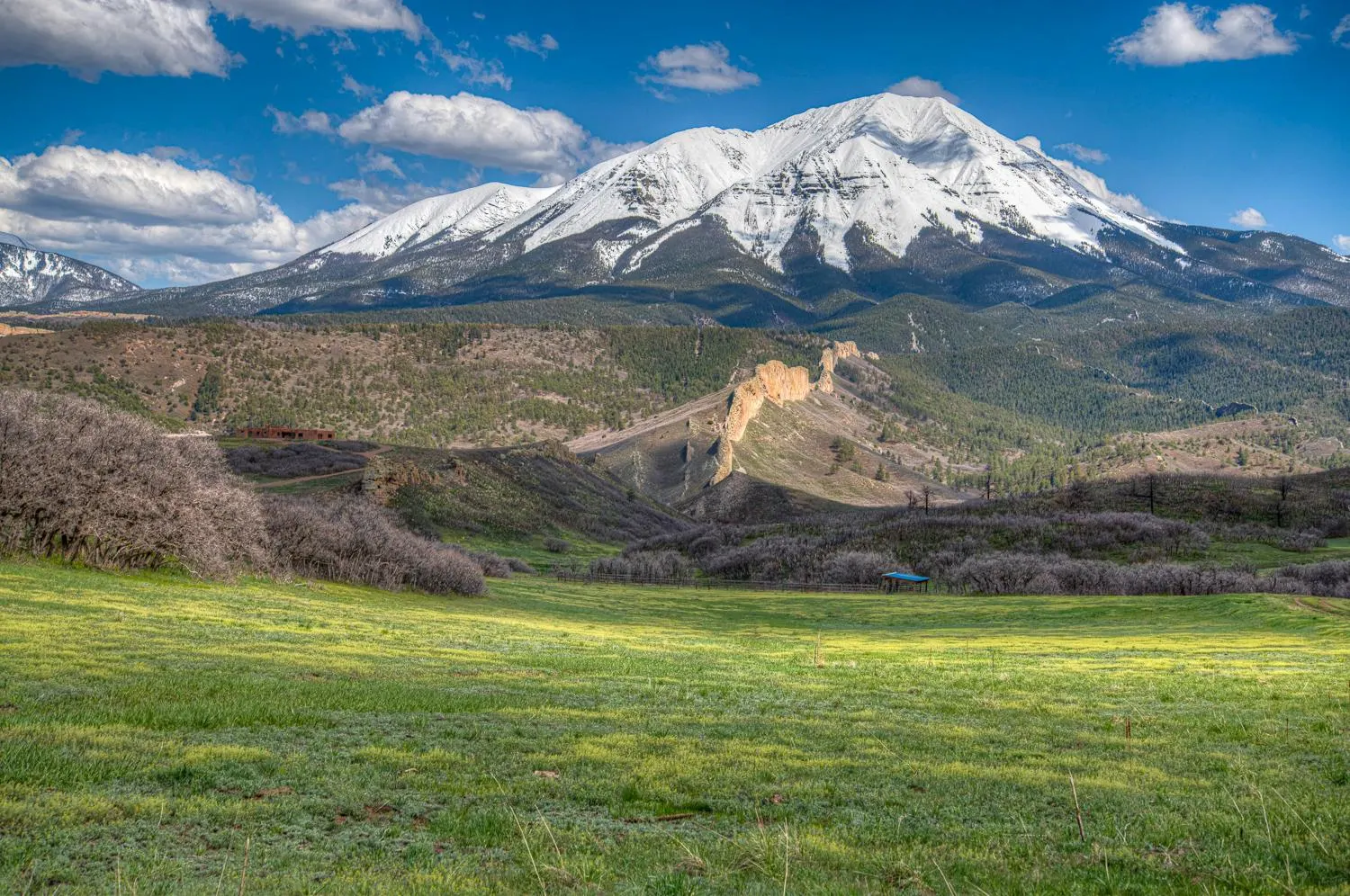The Spanish Peaks rising above a green valley and rocky foreground near Cuchara.