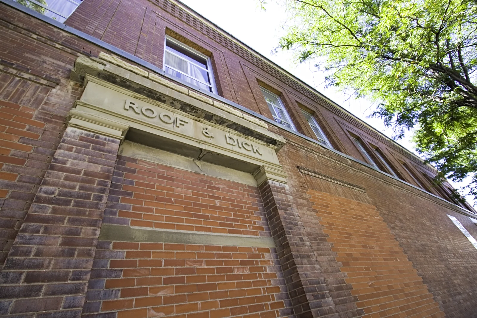 Roof and Dick name carved in stone above the red brick exterior of the historic building.