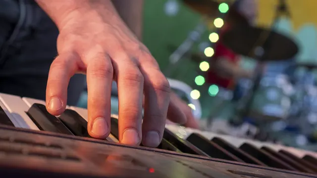 A musician's hand plays a keyboard during a live performance.