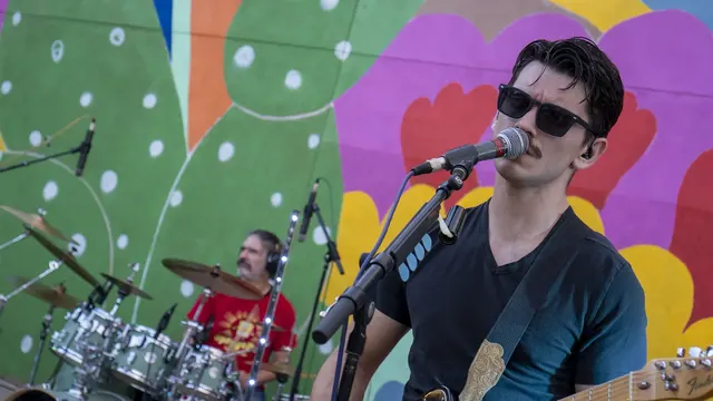 Nash, Vegan Shark's guitarist and vocalist, performs in front of a painted mural while Nathan plays drums behind him.