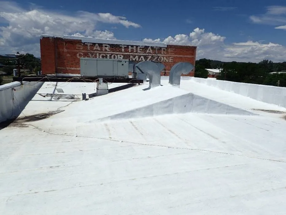 Low roof framing with sloped crickets and the higher stage roof beyond.
