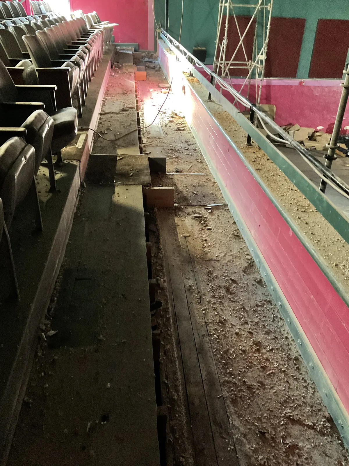 Narrow protected work path running beside the auditorium seats and temporary construction access.