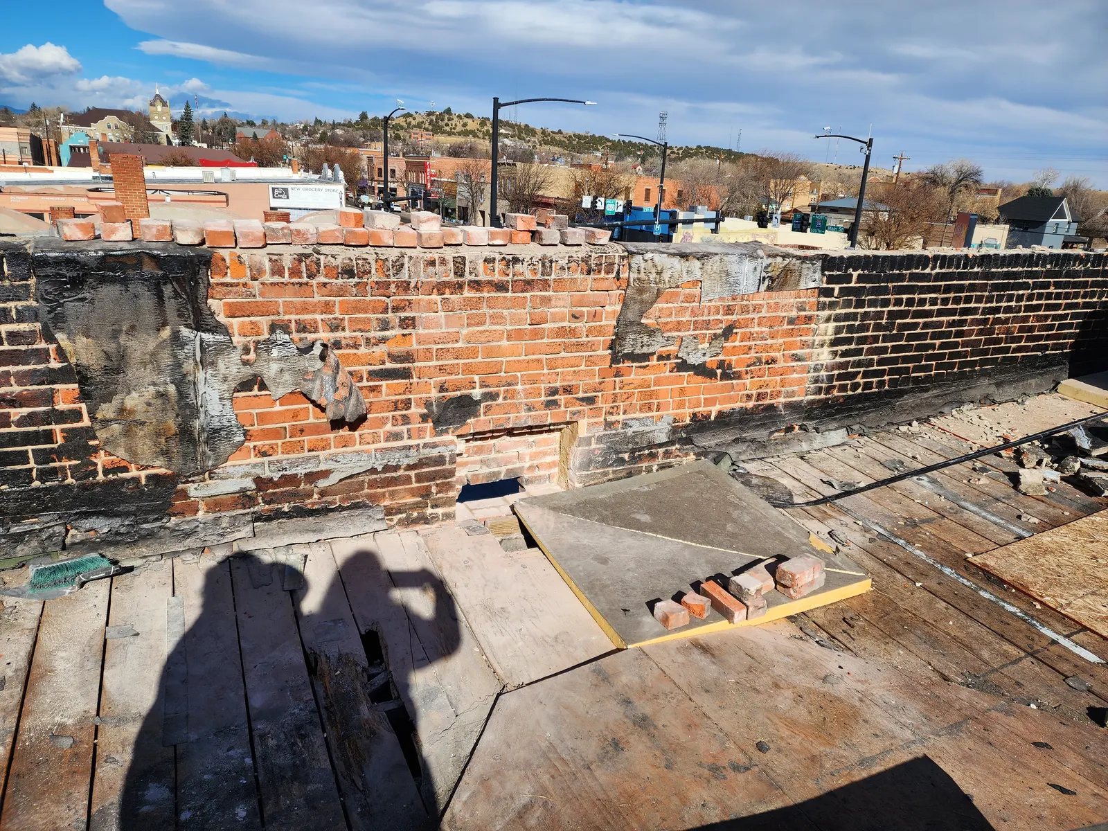 Long exposed brick parapet above the open roof deck during masonry repairs.