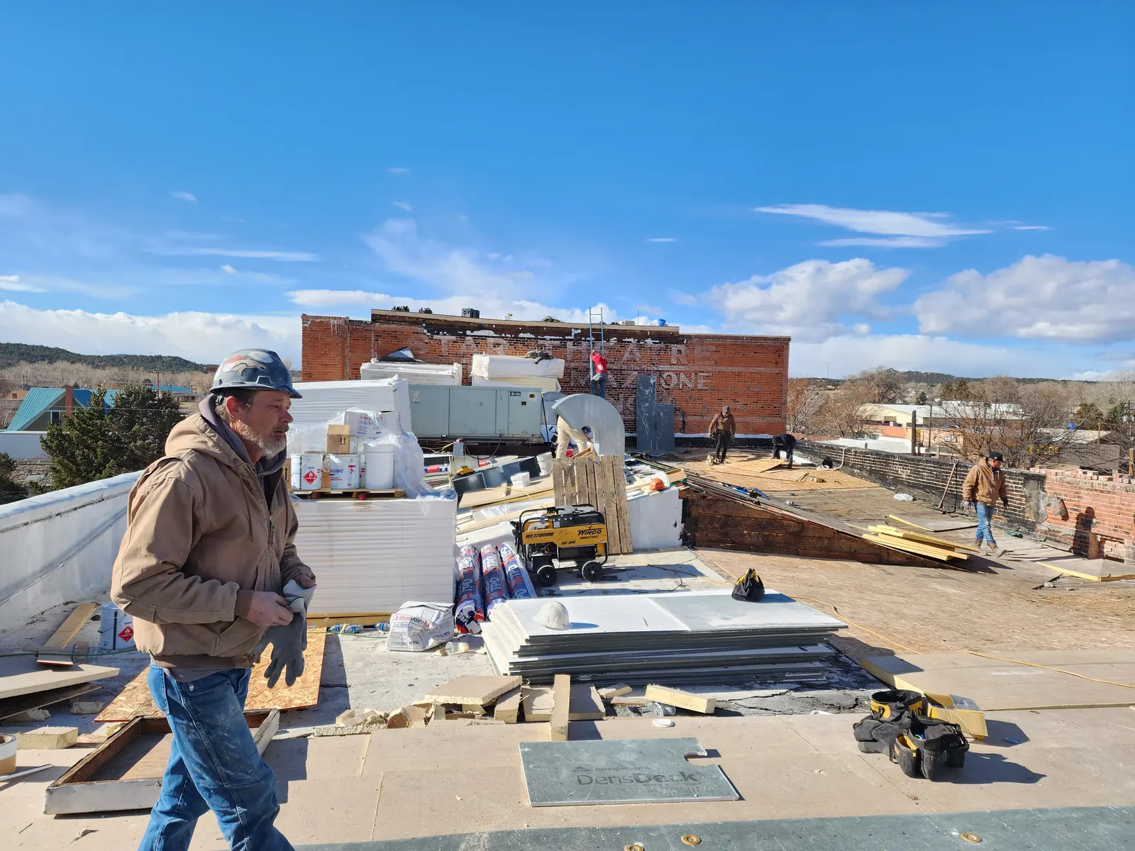 Worker, tools, and roofing materials spread across the Fox roof during Phase 1.