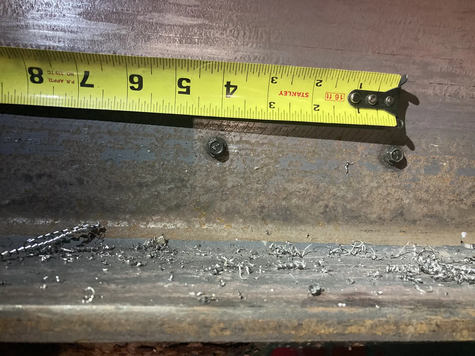 Tape measure held across a steel connection during a field fit check.