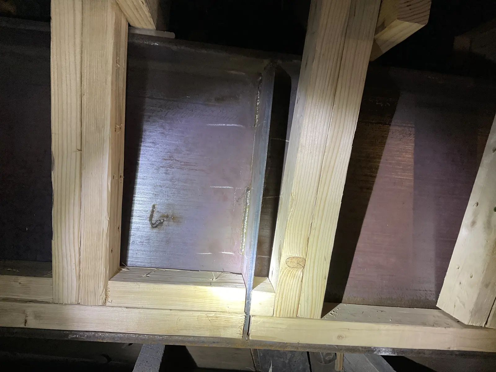 Close view of new timber braces fitted around a dark steel support inside the roof structure.