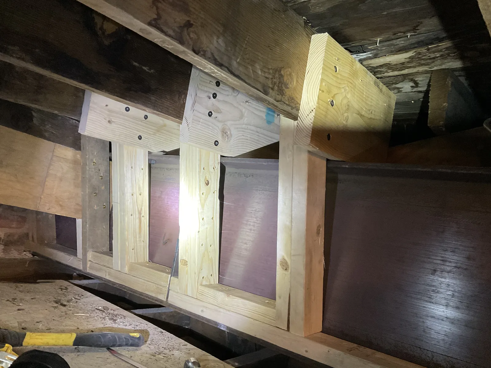 Completed timber reinforcement and a steel beam installed beside dark historic roof framing.
