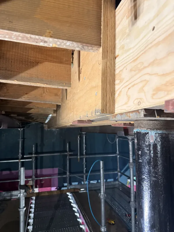 Timber reinforcement and temporary supports beneath the balcony framing.